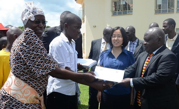 (L-R) Parent and one of the beneficiaries receiving a certificate of recognition from Mr. Yusuf Nsubuga, director of secondary education at the Ministry of Education and Sports, Looking on is Ms Wei Chai , Head of Corporate Affairs, CNOOC Uganda at CNOOC Best Performers Awards in Hoima